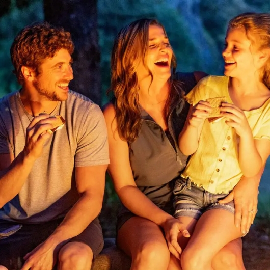 family smiling and laughing by outdoor bonfire